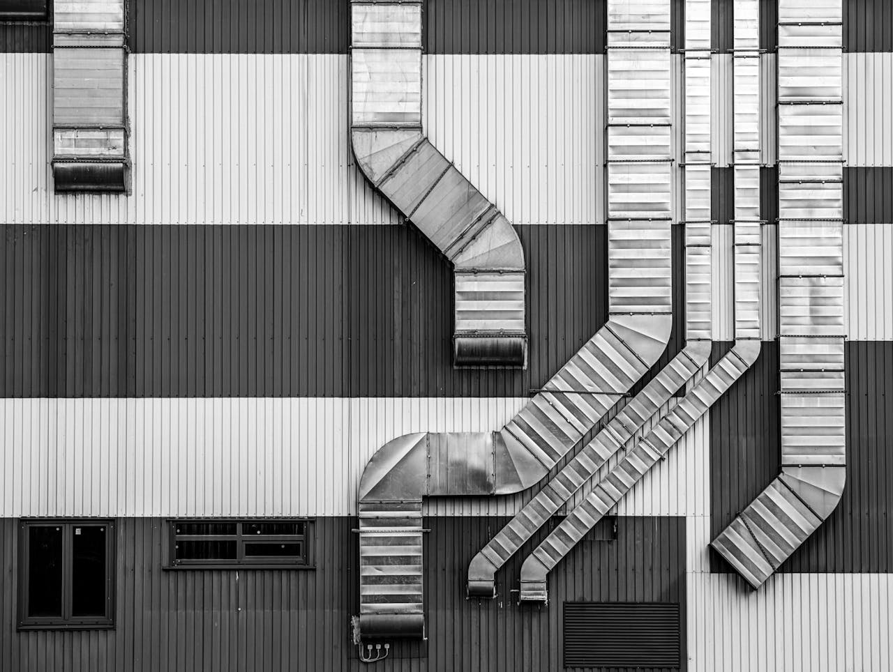 services-01 Monochrome image showcasing industrial ductwork and vents on a striped building exterior.