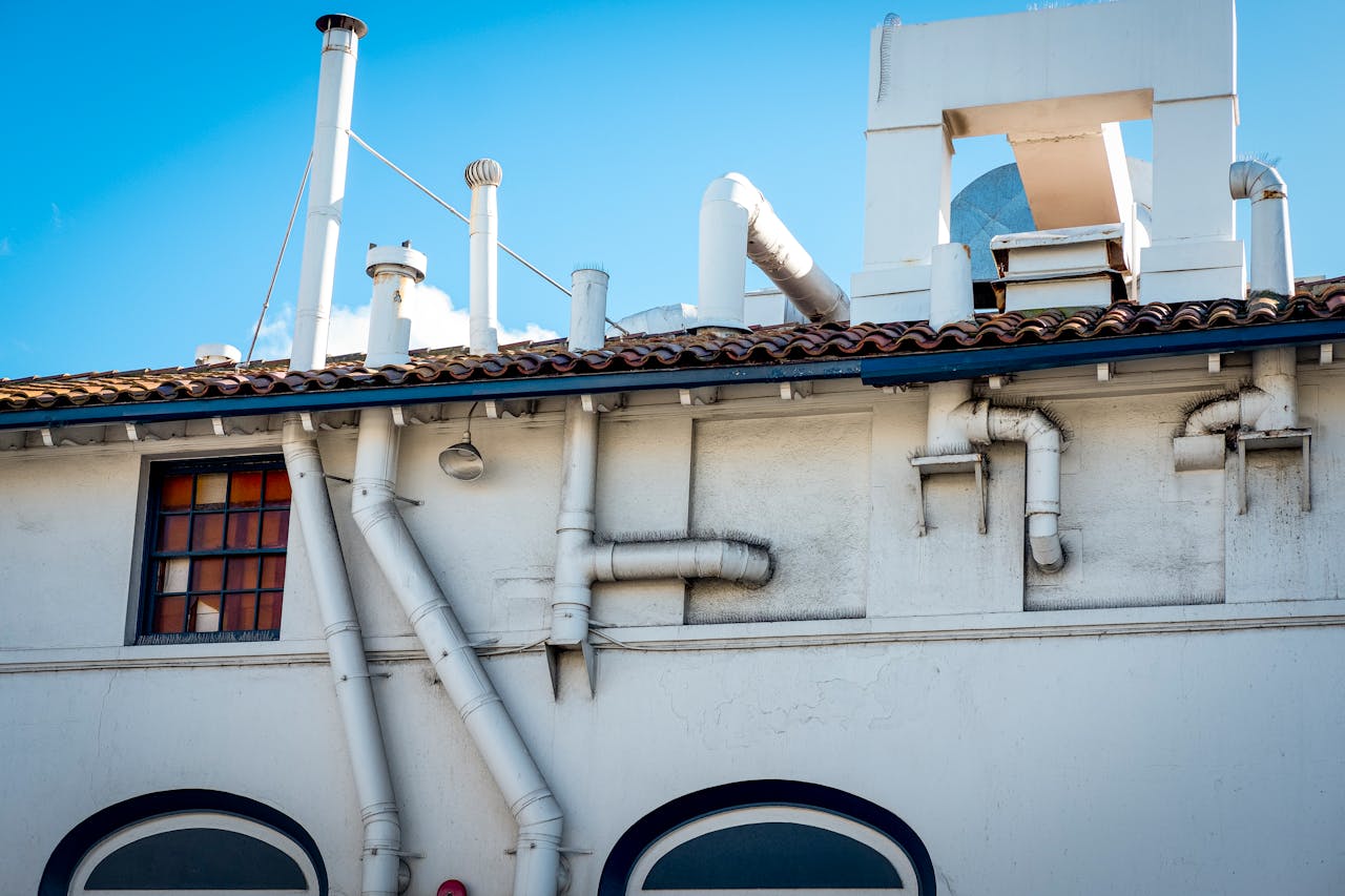 services-02 White building with chimneys and ventilation pipes on a clear day.