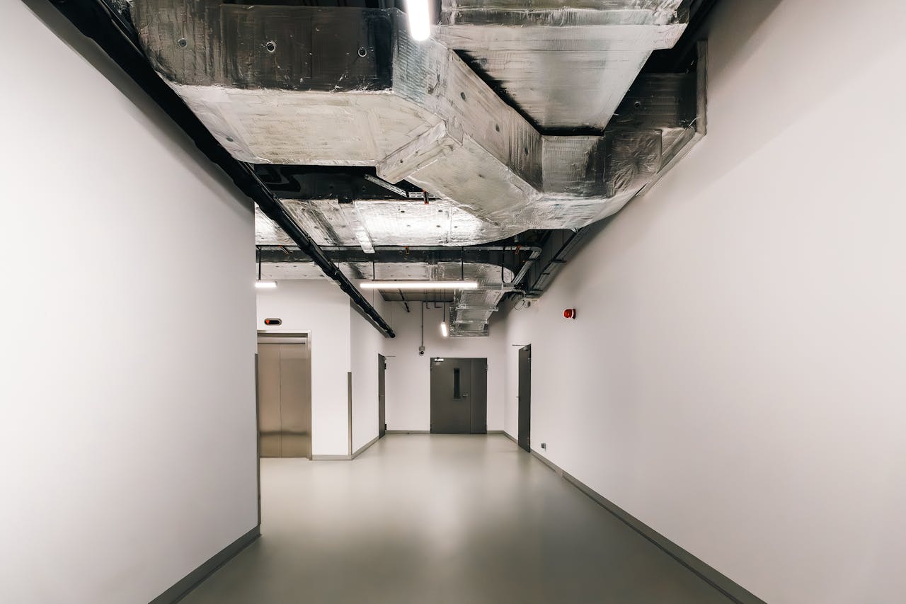 services-03 Spacious industrial hallway featuring exposed HVAC ductwork and modern design elements.