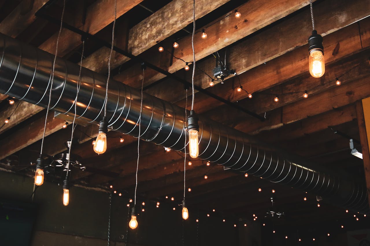 hero-img-01 Wooden ceiling featuring industrial hanging lights and exposed ductwork for a modern rustic look.